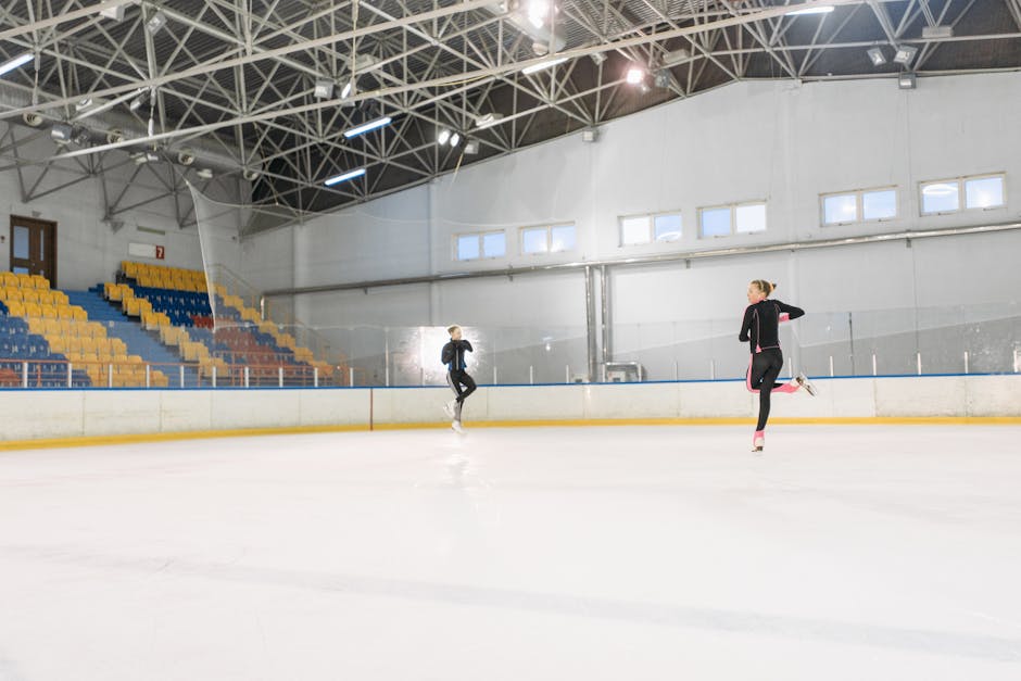 Two figure skaters training on an indoor ice rink, showcasing grace and motion.